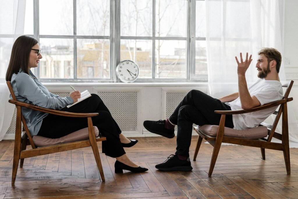 To personer sitter i hver sin stol og snakker sammen, som i en oppfølgingssamtale etter en hendelse.